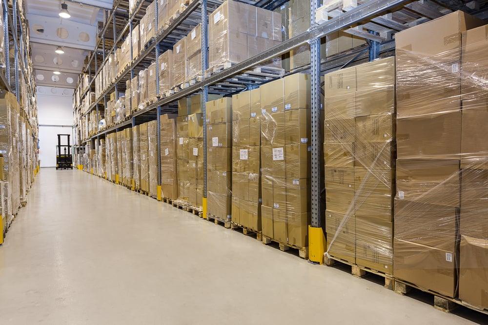 Pallets of wrapped cartons stored along a warehouse aisle